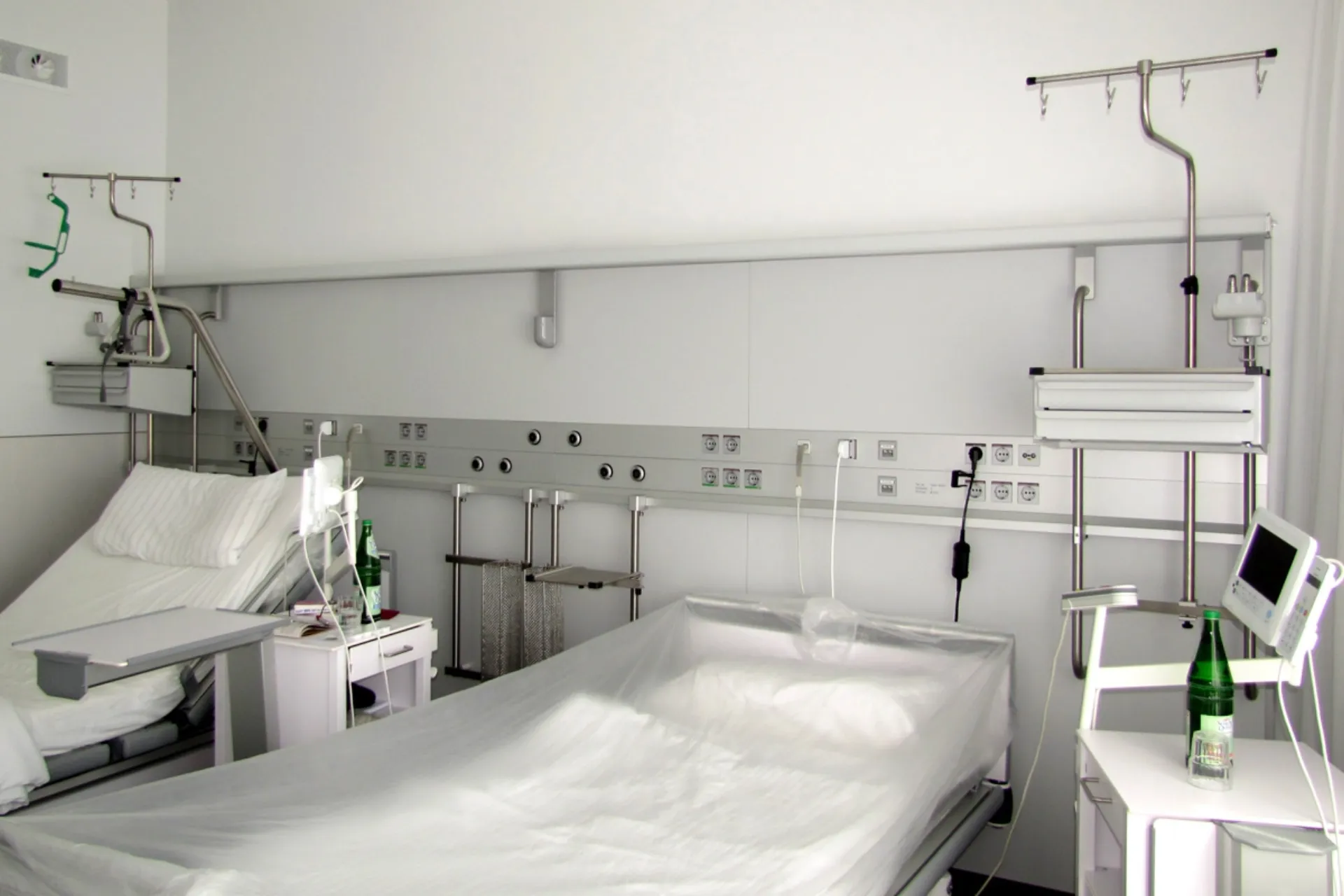 Ein Zweibett-Krankenzimmer mit horizontaler Geräteschiene an der Rückwand.