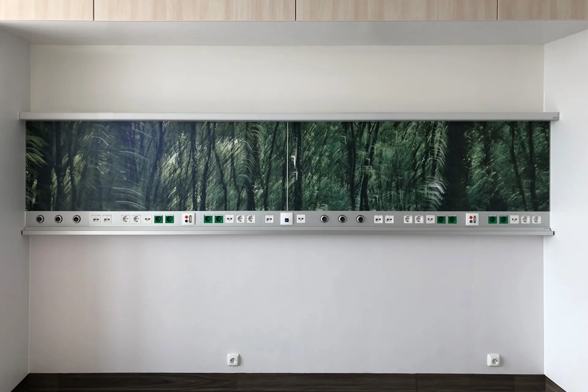 Wandmontierte Versorgungseinheit mit Steckdosenleiste und mit digital bedrucktem Motiv eines dunklen Waldes